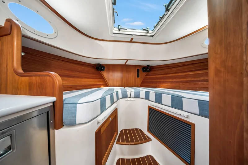 Slide: The Image of 2019 Hinckley Picnic Boat 34 interior with wood accents and striped cushions. - 10