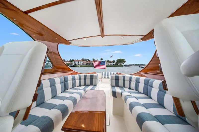 Slide: The Image of 2019 Hinckley Picnic Boat 34 interior with striped seating and wooden accents, overlooking water. - 5