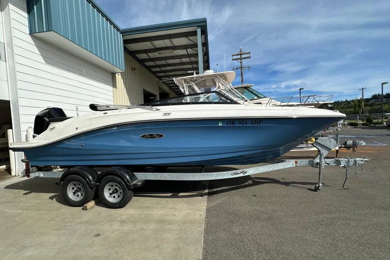 The Image of 2023 Sea Ray SPX 230 Outboard boat on trailer, blue hull, parked outdoors. - 0