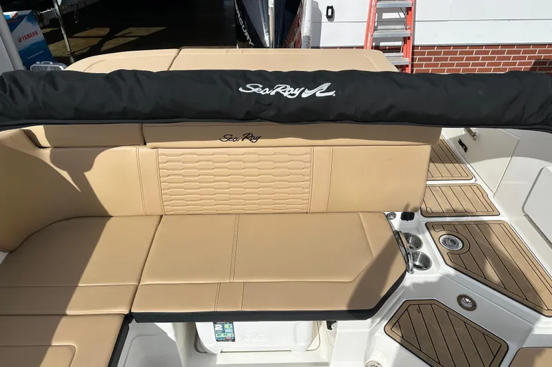 Slide: The Image of 2023 Sea Ray SPX 230 Outboard boat interior with tan seating and wood accents. - 10