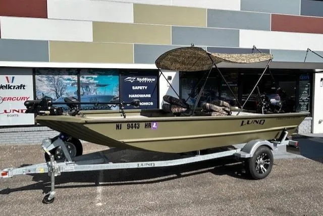 Slide: The Image of 2024 Lund 1660 Predator Tiller boat on trailer, parked outside a store. - 3