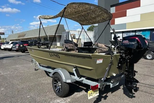 Slide: The Image of 2024 Lund 1660 Predator Tiller boat with canopy, parked on a trailer in a lot. - 5