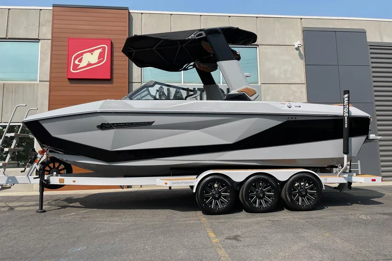 The Image of 2026 Nautique Super Air Nautique G23 boat on trailer, parked outside a building. - 1