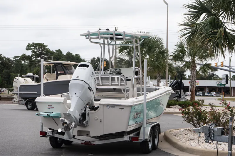 Slide: The Image of 2026 Carolina Skiff 21 Ultra Elite boat on trailer, parked outdoors near palm trees. - 6