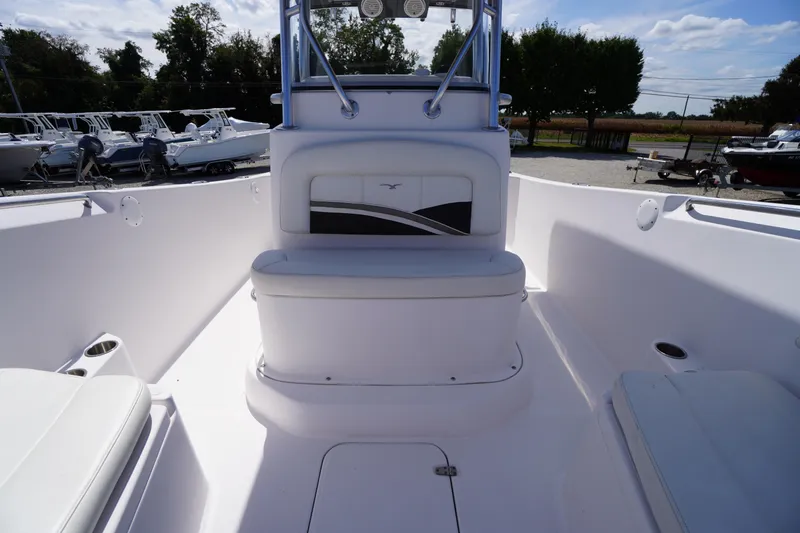 Slide: The Image of 2016 Pro-Line 29 Grand Sport boat interior with seating and console, docked outdoors. - 16
