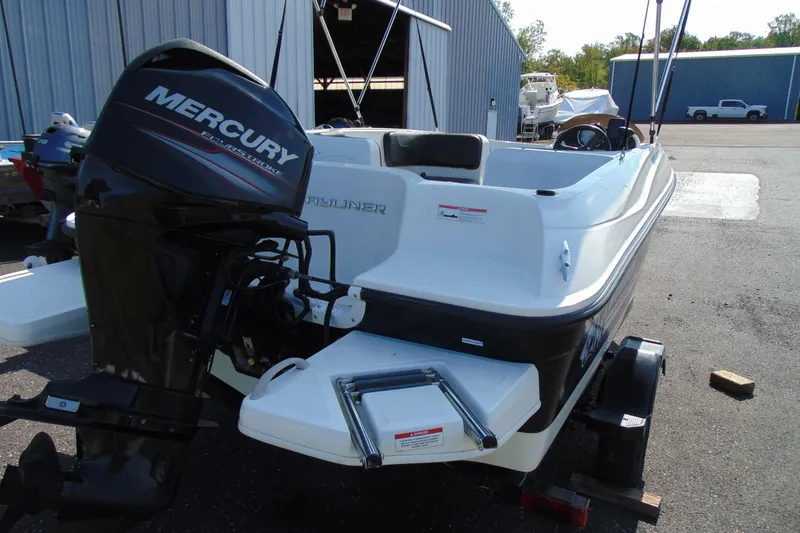 Slide: The Image of 2016 Bayliner 160 Element boat with Mercury outboard engine, parked near a warehouse. - 4