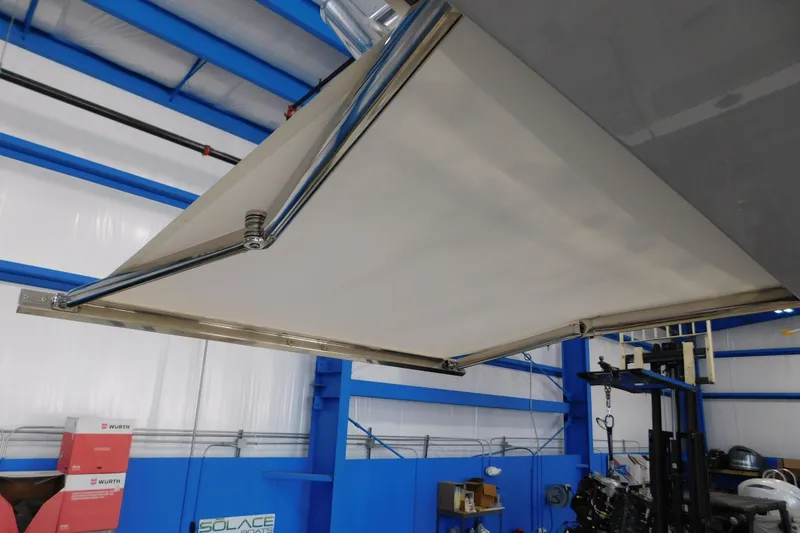 Slide: The Image of 2022 Pursuit S 328 Sport boat with extended sunshade in a blue and white indoor setting. - 45