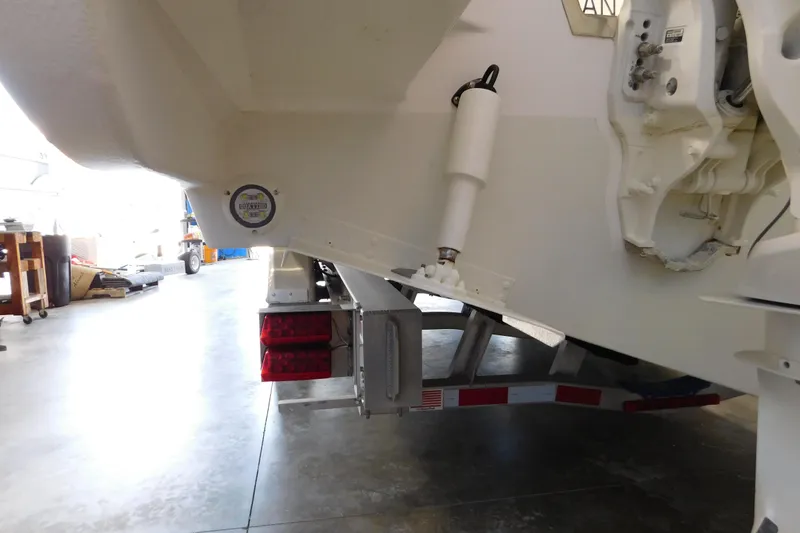Slide: The Image of 2022 Pursuit S 328 Sport boat on trailer in garage, showing rear view and hydraulic components. - 76