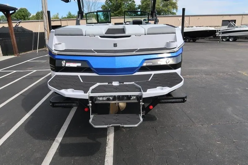 Slide: The Image of 2026 MasterCraft NXT22 boat rear view in parking lot, showcasing sleek design. - 10