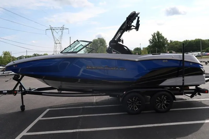 Slide: The Image of 2026 MasterCraft NXT22 boat in blue on trailer outside Boat Masters store. - 3