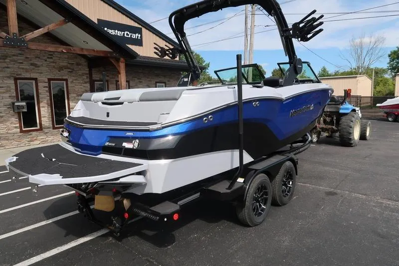 Slide: The Image of 2026 MasterCraft NXT22 boat on trailer, parked outside dealership. - 6