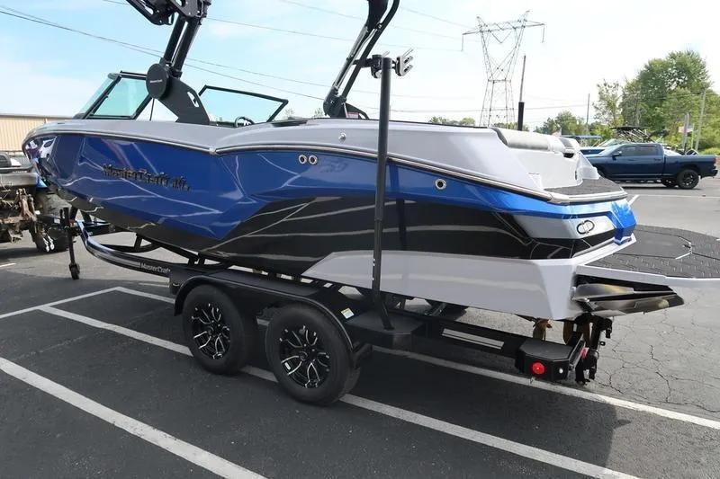 Slide: The Image of 2026 MasterCraft NXT22 boat on trailer, blue and black design, parked outdoors. - 8