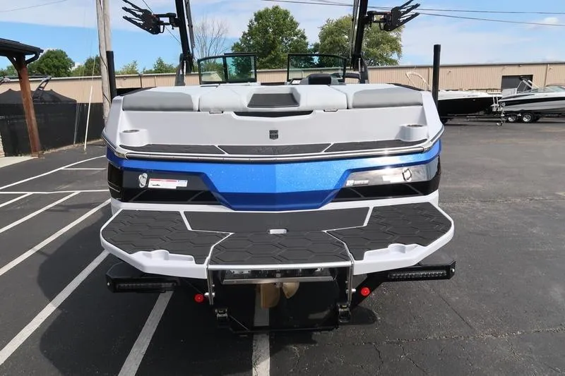 Slide: The Image of 2026 MasterCraft NXT22 boat on trailer, blue and black design, parked outdoors. - 9
