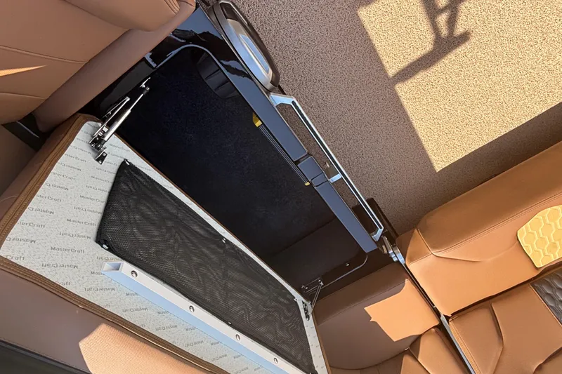 Slide: The Image of 2026 MasterCraft XT24 boat interior with open storage compartment and tan seating. - 14