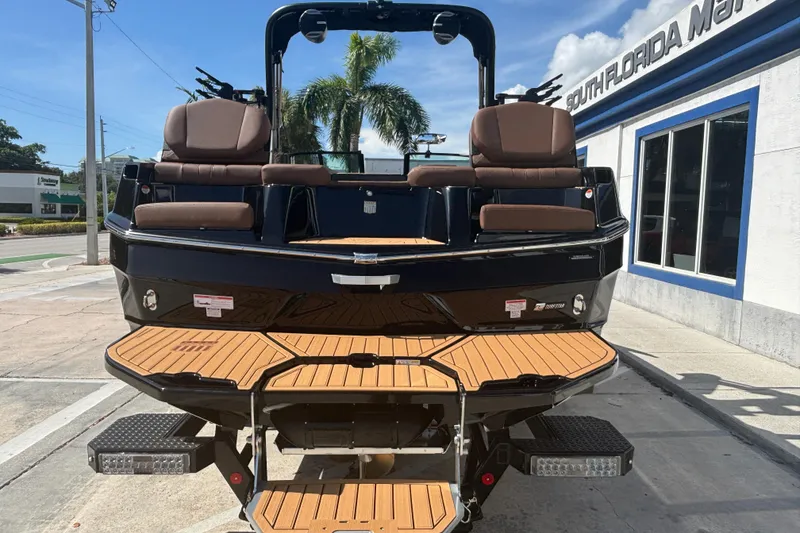Slide: The Image of 2026 MasterCraft XT24 boat with brown seating and teak deck, parked outdoors. - 3