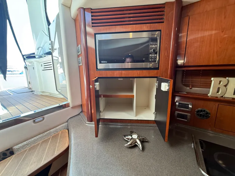 Slide: The Image of 2004 Sea Ray 390 Sundancer interior with microwave and open cabinet. - 21