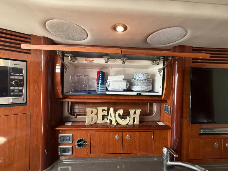 Slide: The Image of Interior of 2004 Sea Ray 390 Sundancer yacht with wooden cabinetry and kitchen essentials. - 22