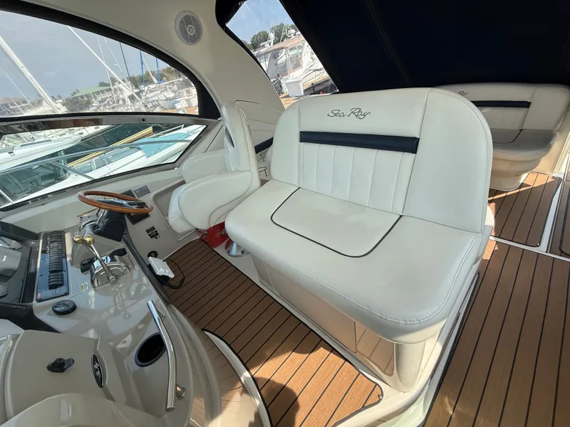 Slide: The Image of 2004 Sea Ray 390 Sundancer cockpit with white seating and wooden flooring. - 5