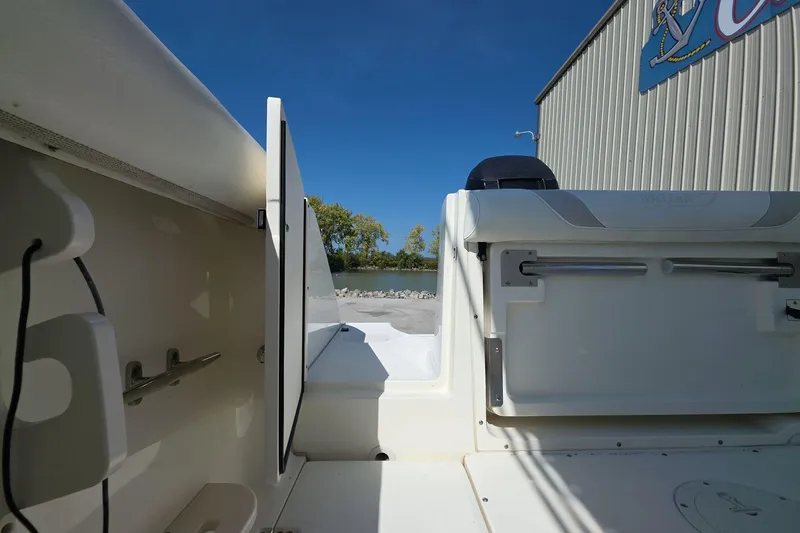 Slide: The Image of 2006 Boston Whaler 240 Outrage boat interior, featuring seating and storage, under clear blue sky. - 9
