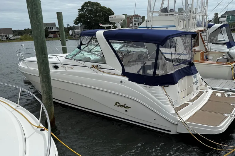 The Image of 2004 Rinker 342 boat docked with blue canopy, in a marina setting. - 1