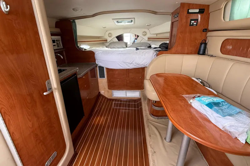 Slide: The Image of 2004 Rinker 342 yacht interior with wood finish, kitchenette, and cozy sleeping area. - 10