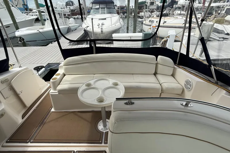 Slide: The Image of 2004 Rinker 342 boat interior with white seating and round table at marina. - 11