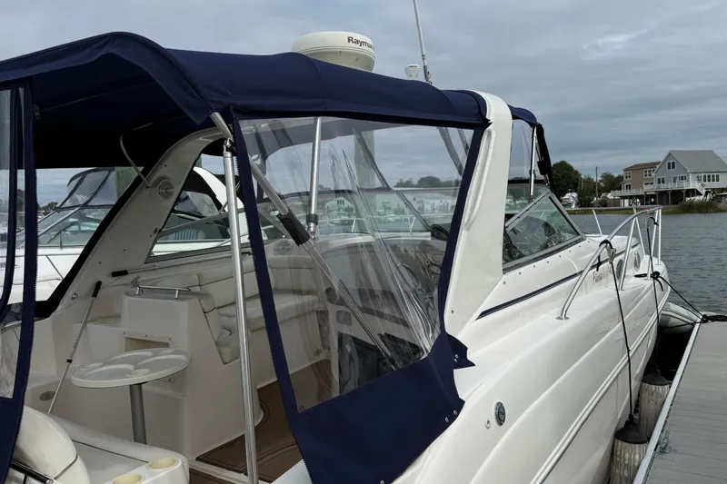 Slide: The Image of 2004 Rinker 342 boat docked, featuring a blue canopy and spacious interior seating. - 13