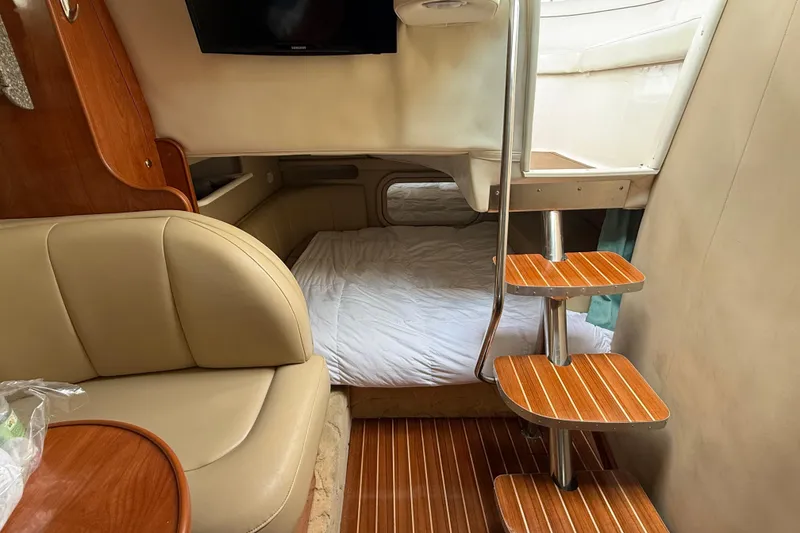 Slide: The Image of Interior of 2004 Rinker 342 boat with cozy seating, bed, and wooden stairs. - 7