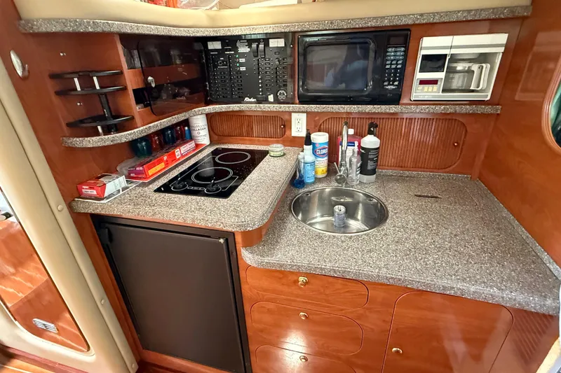 Slide: The Image of 2004 Rinker 342 yacht kitchen with stove, sink, microwave, and storage cabinets. - 9