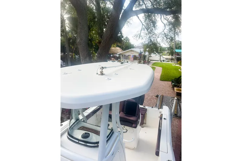 Slide: The Image of 2017 Tidewater 230 CC Adventure boat, white exterior, docked near a tree-lined path. - 16