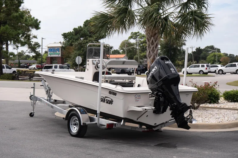 Slide: The Image of 2026 Carolina Skiff EV180 Sea Skiff on trailer, parked near palm tree. - 4