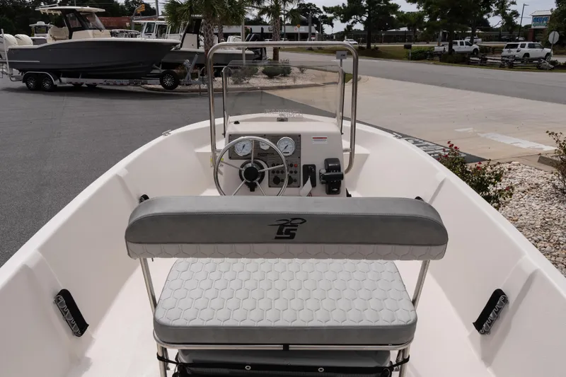 Slide: The Image of 2026 Carolina Skiff EV180 Sea Skiff interior with steering console and seating, parked outdoors. - 8