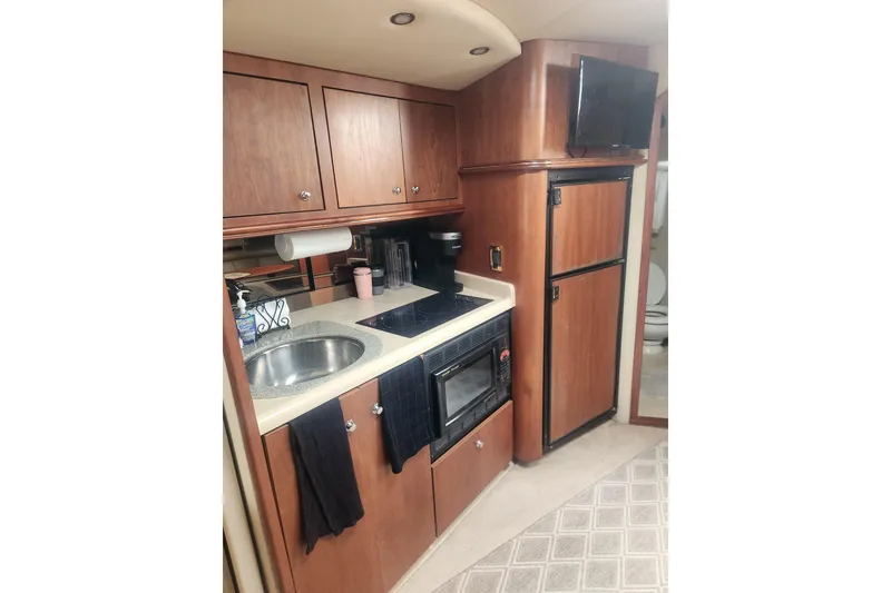 Slide: The Image of 2002 Cruisers Yachts 3870 Express kitchen with wood cabinets, sink, stove, and fridge. - 6