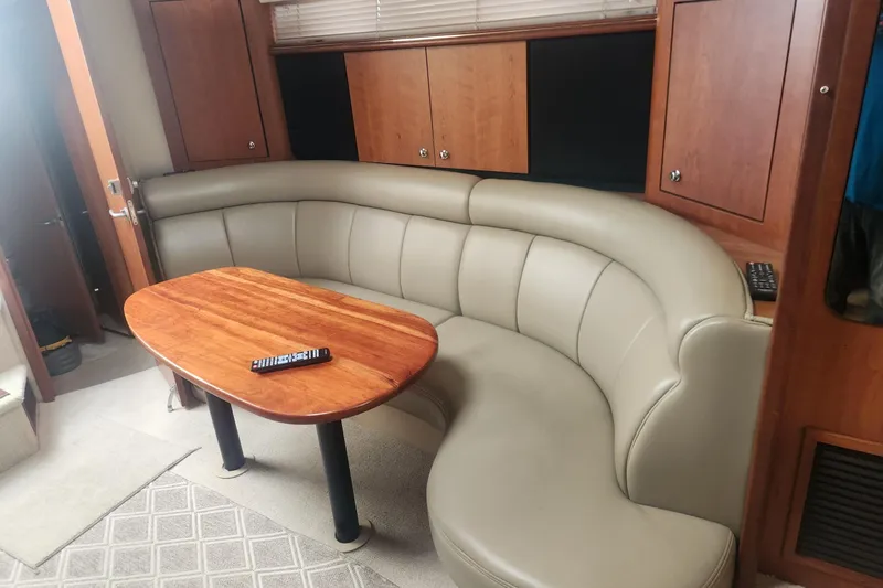Slide: The Image of Interior of 2002 Cruisers Yachts 3870 Express with curved leather seating and wooden table. - 7