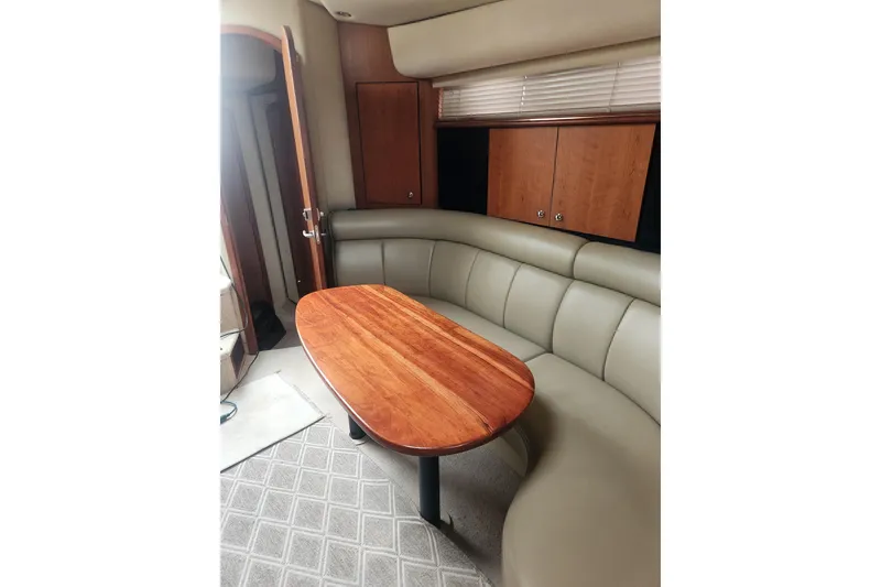 Slide: The Image of Interior of 2002 Cruisers Yachts 3870 Express with curved seating and wooden table. - 8