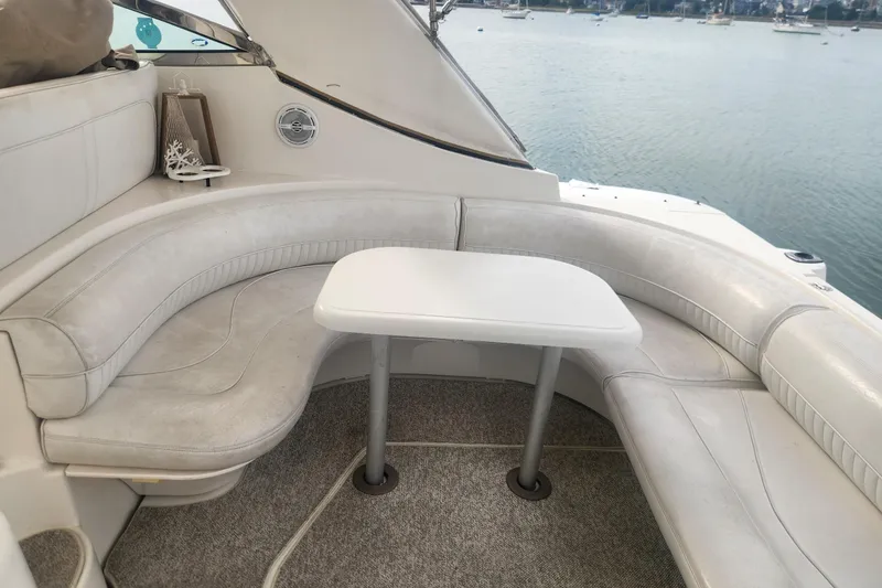 Slide: The Image of 2002 Cruisers Yachts 3870 Express interior with white seating and table, overlooking water. - 1