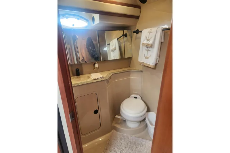 Slide: The Image of 2002 Cruisers Yachts 3870 Express bathroom with toilet, sink, and nautical-themed towels. - 12