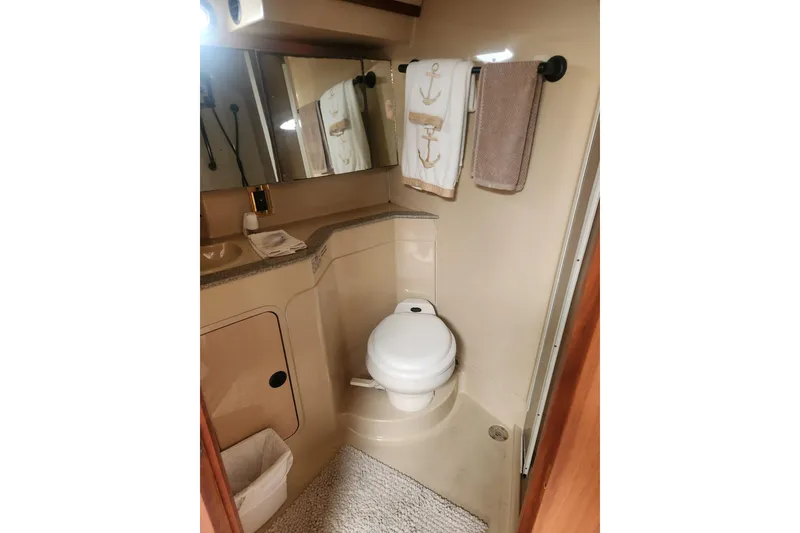 Slide: The Image of 2002 Cruisers Yachts 3870 Express bathroom with toilet, mirror, and nautical-themed towels. - 13