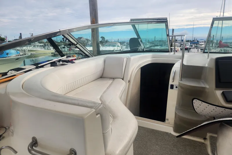 Slide: The Image of 2002 Cruisers Yachts 3870 Express interior with white seating and marina view. - 2
