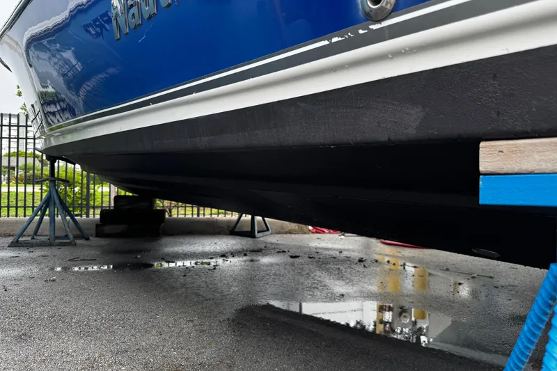 Slide: The Image of 2019 NauticStar 22 XS Offshore boat on stands, blue hull, wet pavement. - 34
