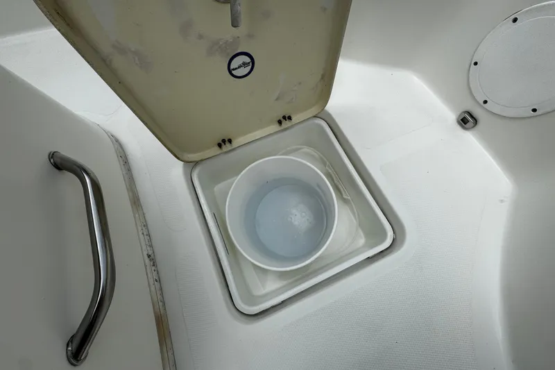 Slide: The Image of 2019 NauticStar 22 XS Offshore boat storage compartment with bucket and handle. - 7