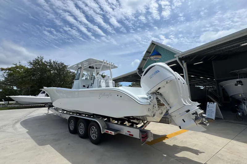 Slide: The Image of 2026 Yellowfin 36 Offshore boat on trailer, parked outside a marina under a cloudy sky. - 17