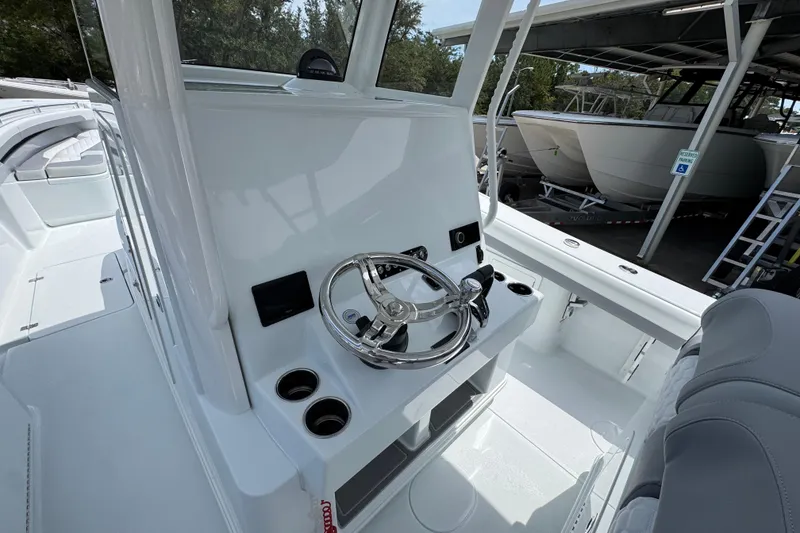 Slide: The Image of 2026 Yellowfin 36 Offshore boat helm with steering wheel and controls, docked in marina. - 31