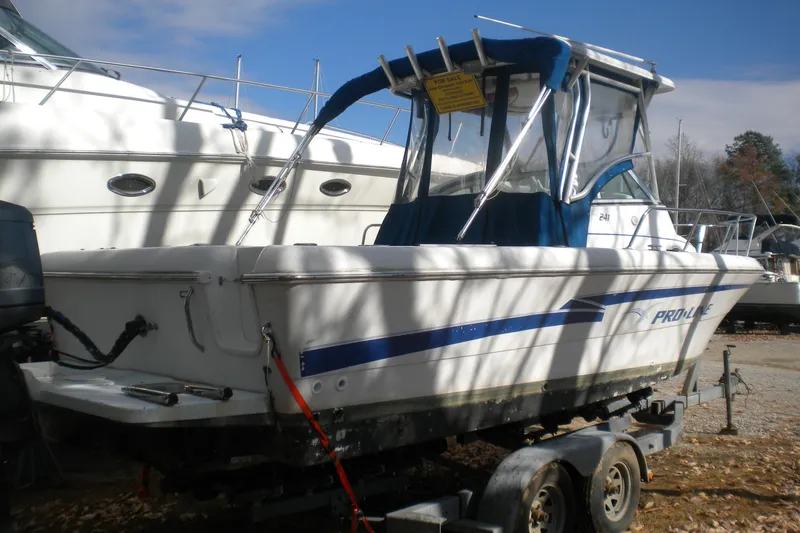 Slide: The Image of 1999 Pro-Line 24 Walkaround boat on trailer, parked outdoors, with blue canopy. - 1