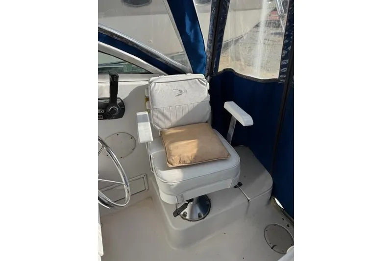 Slide: The Image of 1999 Pro-Line 24 Walkaround boat interior with cushioned captain's chair and blue canopy. - 11