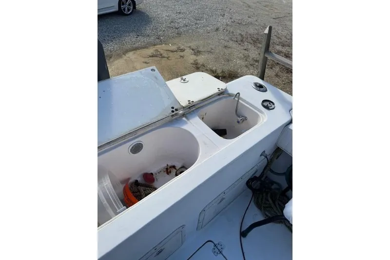 Slide: The Image of 1999 Pro-Line 24 Walkaround boat with open storage compartments and fishing gear. - 14