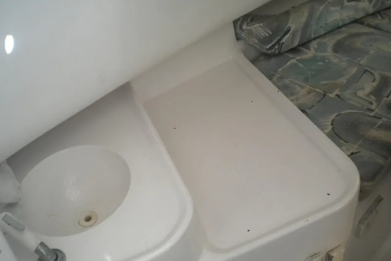 Slide: The Image of 1999 Pro-Line 24 Walkaround boat interior with sink and cushioned seating area. - 16