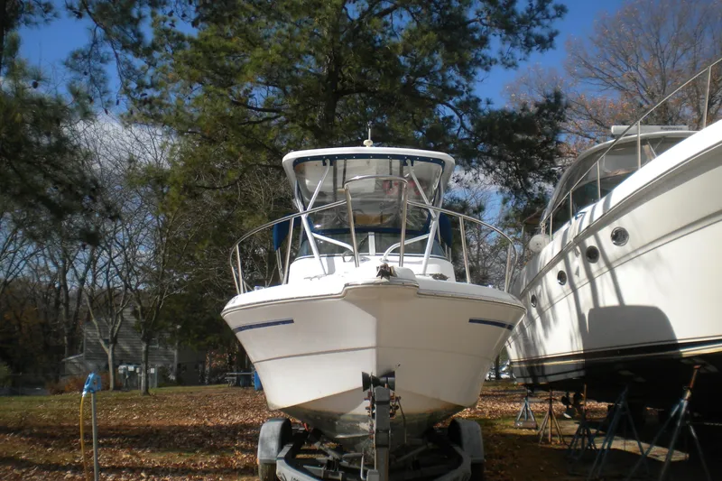 Slide: The Image of 1999 Pro-Line 24 Walkaround boat on trailer, surrounded by trees and other boats. - 2