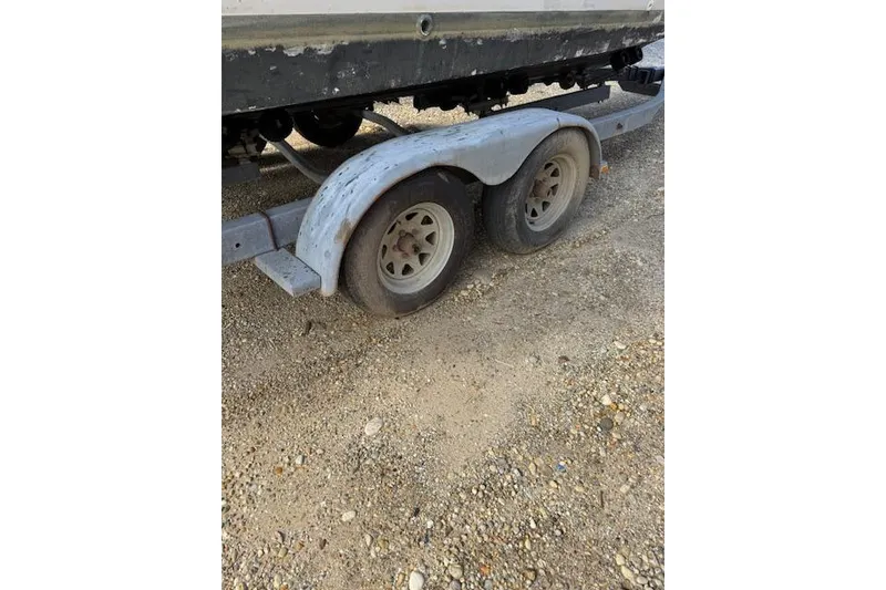 Slide: The Image of Trailer wheels of a 1999 Pro-Line 24 Walkaround boat on gravel. - 22