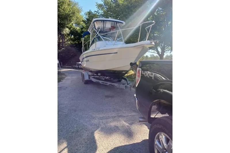 Slide: The Image of 1999 Pro-Line 24 Walkaround boat on trailer, hitched to a black truck. - 4